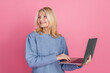 © deagreez - Photo of attractive senior woman hold netbook look empty space dressed stylish blue knitted clothes isolated on pink color background