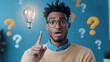 © Roman - A Young Man in a Cozy Sweater Looks Surprised While Raising His Index Finger in Excitement, With a Light Bulb Glowing Above Him Against a Bright Blue Wall Filled With Question Marks