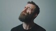 © Lion - Bearded man with a grimace holding his jaw as if experiencing pain, standing against a plain background under soft studio lighting