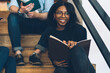 © BullRun - Cheerful young multiracial students studying on stairs in library