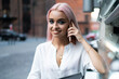 © BullRun - Young confident woman having call on cellphone in city