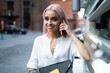 © BullRun - Young confident woman having call on cellphone in city