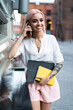© BullRun - Young cheerful woman having call on smartphone in city