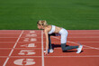 © Yevhen - Girl at the start is ready to run and win. Female athlete alone on the athletic track, sprint running. Athlete on the starting. Young sportswoman sprint on a running track outdoors on stadium