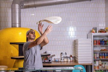 Chef tossing pizza dough. Pizza chef makes the pizza dough spin in the air to make it thin and soft. Pizza maker spinning dough in kitchen