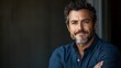 © Alexandr - A man with a beard and gray hair is smiling and looking at the camera. He is wearing a blue shirt and has his arms crossed