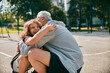 © Marko Geber - Grandfather playing basketball with grandson at outdoor court