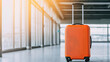 © Janjira - A stylish orange suitcase stands alone in a modern airport terminal, symbolizing travel, adventure, and the excitement of new journeys.