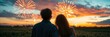 © somsak - Young couple standing in a field, gazing at colorful fireworks against the backdrop of a stunning sunset, young, fireworks, event