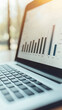© wasan - Close-up view of a laptop displaying financial growth graph and data analysis.