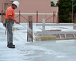 © peuceta - Construction carpenter waters the surface of a reinforced concrete floor slab on a construction site. concrete curing process