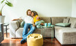 © Davide Angelini - Cheerful multiracial couple sitting on sofa in the living room - Happy family moving in new home - Real estate and stylish furniture concept