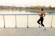 © BGStock72 - Early morning jogger enjoys a brisk run along a scenic waterfront pathway at sunrise in a vibrant urban park setting