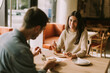 © BGStock72 - A joyful couple enjoys coffee and pastries in a cozy cafe during a sunny afternoon