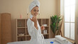 © Krakenimages.com - A beautiful young woman with blonde hair in a spa center, wearing a white robe, smiles while standing in an indoor wellness room, suggesting a serene and rejuvenating experience.