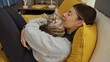 © Krakenimages.com - A young hispanic woman cuddles with her tabby cat on a bed in a cozy bedroom, highlighting the indoor comfort of a home setting.