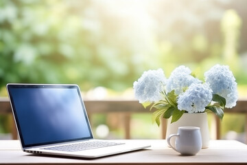Laptop mockup on a table with blue flowers in a vase, blurred background, natural light, window view, home office concept.