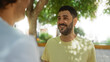 © Krakenimages.com - Two men having a friendly conversation in an urban park under the shade of trees, reflecting their bond, happiness, and outdoor enjoyment
