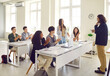 © Studio Romantic - Young girl student standing at the desk in classroom and answering the male teacher with a college or high school students applauding her during a lesson. Education and learning concept.