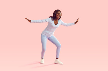 full length portrait of funny afican american girl wearing casual clothes dancing isolated on a pink