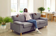 © Studio Romantic - African american relaxed woman sitting on comfortable couch in the living room at modern home with closed eyes and smiling. Young girl enjoying quiet time alone in the room resting and dreaming.