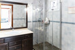 © ADDICTIVE STOCK - Elegant tiled bathroom with glass shower enclosure and vanity