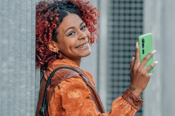 portrait african american woman with mobile phone on the street outdoors