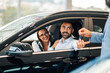 © Zamrznuti tonovi - Happy couple inside car receiving keys from a salesperson in a dealership