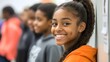 © James - Portrait of cheerful African American teenage student smiling in school hallway with classmates blurred in background, copy space