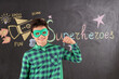 © Pixel-Shot - Teenage boy dressed as superhero near blackboard