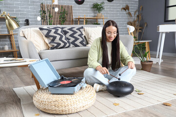 Wall Mural - Young woman with record player playing glucophone at home