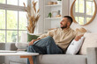 © Pixel-Shot - Young man sitting on comfortable sofa at home