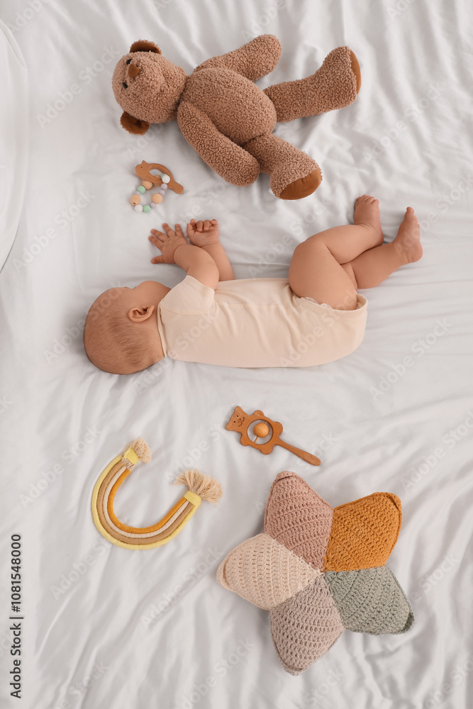 Cute little baby sleeping with toys on bed, top view