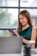 © David - Business Asian woman hold phone and use laptop at the workplace. Project stats financial data sales charts on laptop and cellphone Asian finance concept