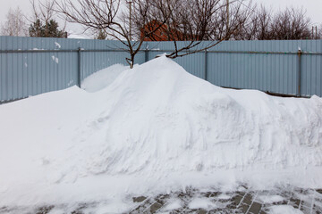 Wall Mural - A snow pile is on the ground next to a fence