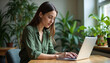 © Ruslan Gilmanshin - Young woman working remotely in a calming home office surrounded by indoor plants. Natural lighting and biophilic design create perfect environment for focused productivity and work-life balance