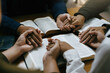 © Deemerwha studio - Christian worship and pray. Christian group of people holding hands praying worships together to believe and Bible on a wooden table for devotional for prayer meeting concept.