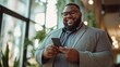 © RaptorWoman - A cheerful professional in a suit smiles at his smartphone, embodying business success and connectivity in a modern office setting.