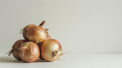 Wall Mural - Pile of whole brown onions with roots on light background