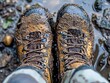 © Bussakon - A pair of rugged hiking boots stained with mud after a long trek through a forest