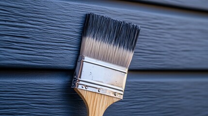 A close-up of a paint brush resting against a freshly painted blue wall.