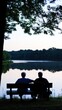 © Trionorejo - A serene lakeside scene featuring two people sitting on a bench, enjoying nature together.