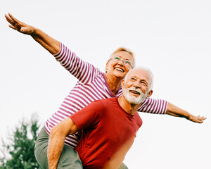 Wall Mural - woman man outdoor senior couple happy lifestyle retirement together smiling love piggyback active ma