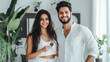 © Maksym - A happy Indian couple standing in their stylish, light-filled living room, holding keys to their new apartment with a sense of joy, with elegant decor and a touch of greenery.