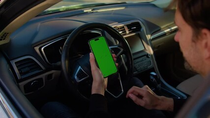Man sits on driver seat using car sharing app on smartphone