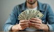 © Vitalii - Man is holding bundle of dollar bills in his hands. The concept of wealth and abundance