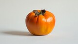 A single persimmon fruit, with its vibrant orange color, is shown against a plain white backdrop.