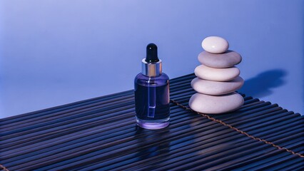 Skincare bottle and stacked stones on a spa mat with blue background