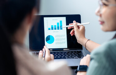 Close-up of two people's hands reviewing financial documents. A pie chart displays 