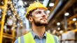 © makappa - A young engineer wearing a yellow hard hat and safety glasses looks up at a glowing network of lines and points above his head, reflecting the future of smart factories and industrial automation.